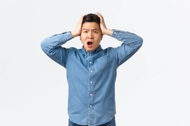 Şaşırmış ve endişeli Asyalı bir adam kafasını tutup panik ve inkar içinde sallıyor. Korkunç bir durumla karşı karşıya olan, endişeli ve telaşlı, ne yapacağını bilmeyen, kararsız, yardıma ihtiyacı olan bir adam.