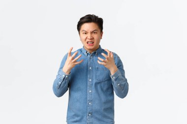Outraged aggressive and pissed-off asian man shaking hands frustrated and mad, frowning and grimacing, swearing angry at someone, feeling furious, standing white background