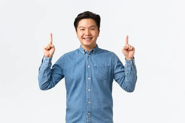 Lachend trots en gelukkig Aziatisch mannelijk model in blauw shirt maken aankondiging, wijzend vingers omhoog naar banner, aanbevelen kopen product, klik link, e-commerce en reclame concept — Stockfoto