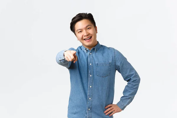 Lachende gelukkig aziatische knappe man in blauw shirt, hebben beugels, wijzende vinger naar de camera, moedigen persoon klik link, vernoemen of kiezen van iemand, staan over witte achtergrond — Stockfoto