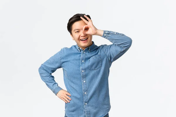 Sorrindo alegre e satisfeito asiático homem mostrando ok gesto sobre olho, olhando através com expressão satisfeita, garantir tudo de bom, recomendar excelente serviço, garantia — Fotografia de Stock