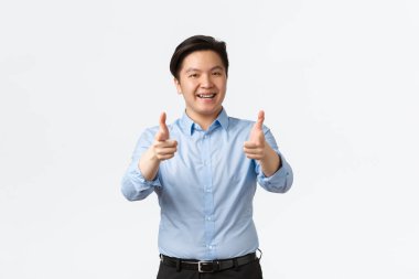 İş, finans ve insan konsepti. Diş teli takmış tatmin olmuş Asyalı işadamı baş parmak gösteriyor. Ofis çalışanı ürün veya iltifat öneriyor. İyi iş, beyaz arka plan.