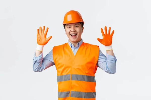 Concepto de sector de la construcción y trabajadores industriales. Alegre sonriente asiático constructor, gerente de construcción en la fábrica con guantes de seguridad, casco y chaqueta reflectante, de pie fondo blanco — Foto de Stock