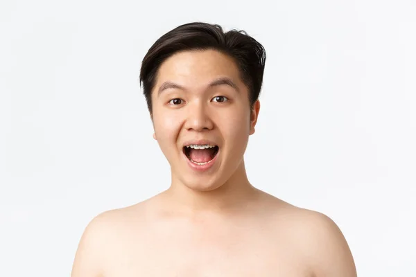 Beauty, skincare and hygiene concept. Close-up of amused and surprised asian young man standing naked over white background and open mouth fascinated, stare something cool — Stock Photo, Image