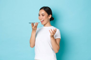 Yaşam tarzı, teknoloji ve insan kavramı. Güzel hevesli Asyalı kız sesli mesaj kaydediyor, akıllı telefon hoparlörü kullanıyor, cep telefonu uygulamasında kendi sesini kaydediyor.