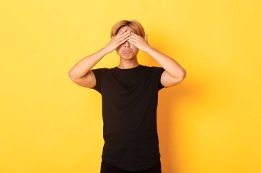 Üzgün ve sefil Asyalı adamın portresi. Gözlerini kapadı ve somurttu, sarı arka planda durdu.