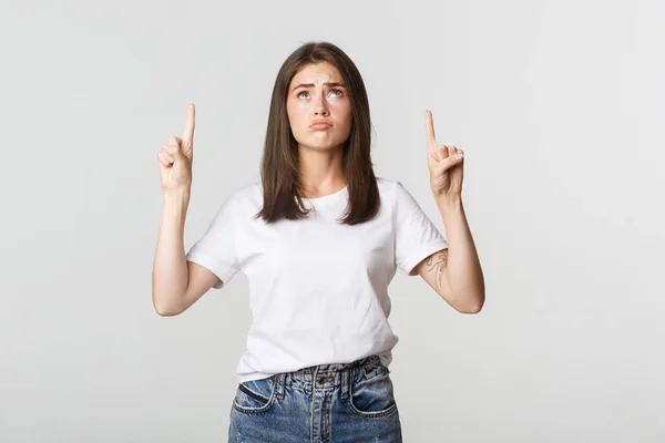 Triste y sombría chica morena enfurruñada, señalando y mirando hacia arriba con pesar — Foto de Stock