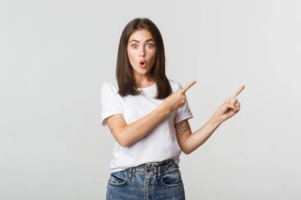 Impressed and amused brunette girl say wow and pointing upper right corner at banner — Stock Photo, Image