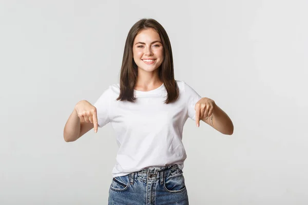 Satisfeito sorridente morena menina apontando os dedos para baixo, recomendo o produto — Fotografia de Stock