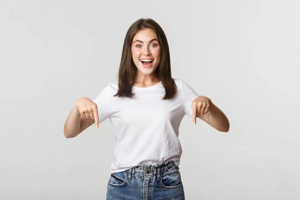 Satisfeito sorridente morena menina apontando os dedos para baixo, recomendo o produto — Fotografia de Stock