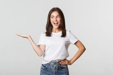 Heyecanlı güzel kız kolunu uzat, elinde bir şey tut ve mutlu görün.