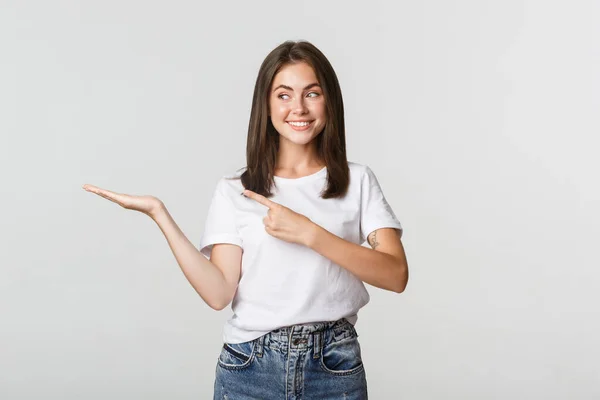 Atractiva joven mujer señalando con el dedo algo que sostiene en la mano — Foto de Stock