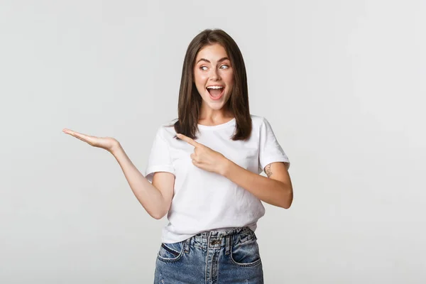 Aantrekkelijke jonge vrouw wijzende vinger naar iets wat ze vasthouden aan de hand — Stockfoto