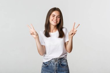 Gülümseyen, barış jestleri yapan neşeli ve çekici genç bir kadın.