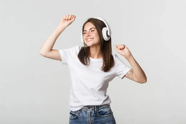 Ξέγνοιαστη ελκυστική κοπέλα χορεύει και ακούει μουσική σε ασύρματα ακουστικά — Φωτογραφία Αρχείου