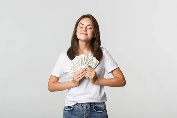 Счастливая и довольная улыбающаяся женщина закрывает глаза и наслаждается деньгами — стоковое фото