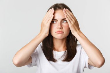 Utanmış ve şok olmuş genç bir kadın facepalm ve garip görünen beyaz bir arka plan.