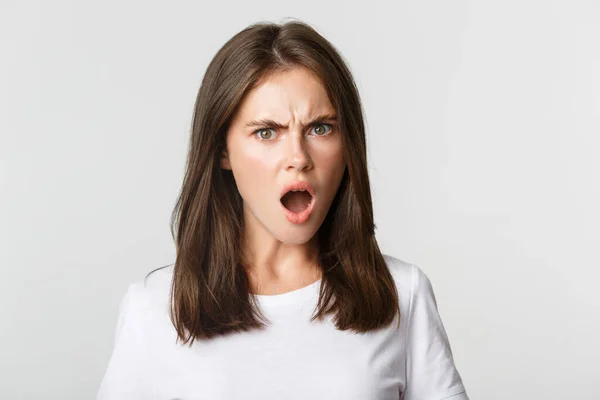 Close-up of outraged insulted young woman looking frustrated and frowning, white background — Stock Photo, Image