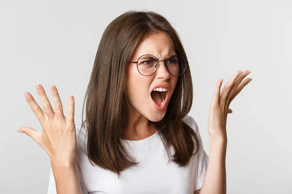 Close-up of angry and outraged beautiful woman in glasses yelling and shaking hands, having an argument — Stock Photo, Image