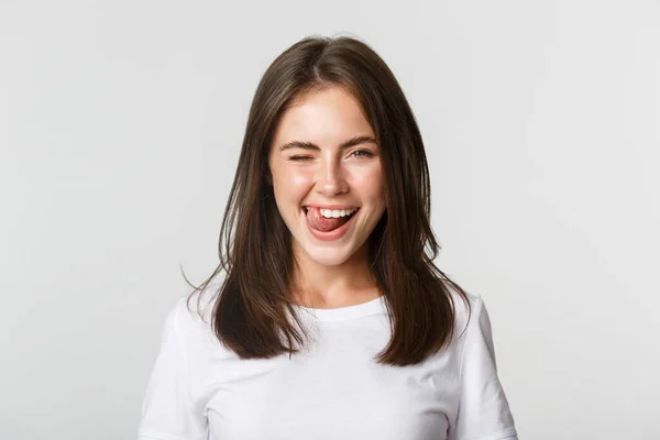 Primer plano de la atractiva joven feliz guiñando alegremente y mostrando la lengua descarada —  Fotos de Stock