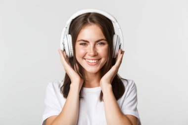 Gülümseyen, kablosuz kulaklıkla müzik dinlemekten hoşlanan güzel mutlu kızın yakın çekimi.