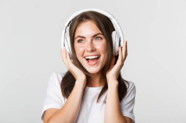 Gülümseyen, kablosuz kulaklıkla müzik dinlemekten hoşlanan güzel mutlu kızın yakın çekimi.