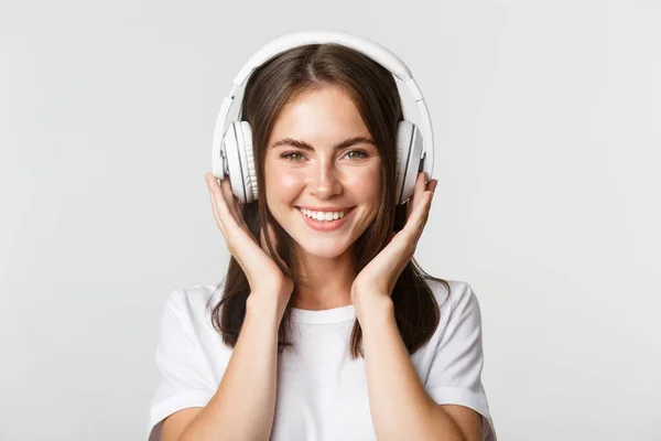 Close-up de bela menina feliz sorrindo, gostando de ouvir música em fones de ouvido sem fio — Fotografia de Stock