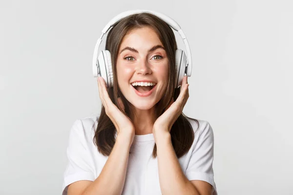 Nahaufnahme eines lächelnden attraktiven brünetten Mädchens, das mit Kopfhörern Musik hört und einen interessanten Podcast genießt — Stockfoto