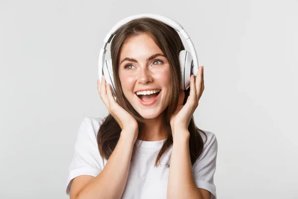 Close-up de bela menina feliz sorrindo, gostando de ouvir música em fones de ouvido sem fio — Fotografia de Stock