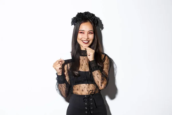 Kép a figyelmes mosolygós ázsiai nő halloween ruhát van egy ötlet, kezében hitelkártya és keres ravasz a bal felső sarokban — Stock Fotó