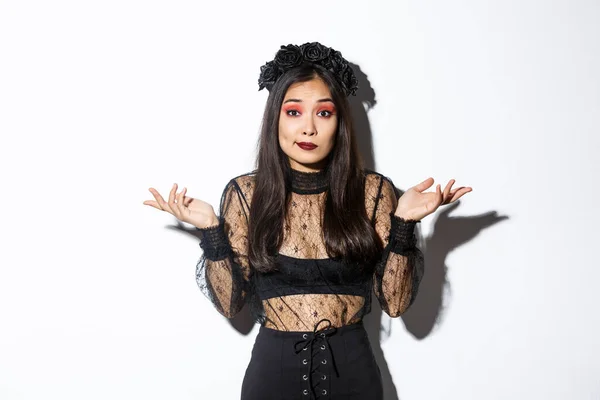 회색 의상을 입고 서서 할로윈 복장을 하고 악마 마녀 복장을 한 채 혼란 스러워 보이는 무심하고 무관심 한 아시아인 소녀의 이미지 — 스톡 사진