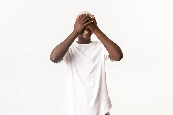 Портрет счастливого африканско-американского молодого парня, закрытые глаза и улыбающиеся, веселые, ожидая сюрприза, стоя на белом фоне — стоковое фото