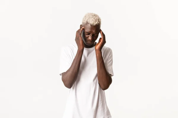 Portret van een duizelingwekkende Afrikaans-Amerikaanse blonde man, hoofdpijn voelen, grimmig zijn en buigen van pijn, migraine hebben, witte achtergrond hebben — Stockfoto