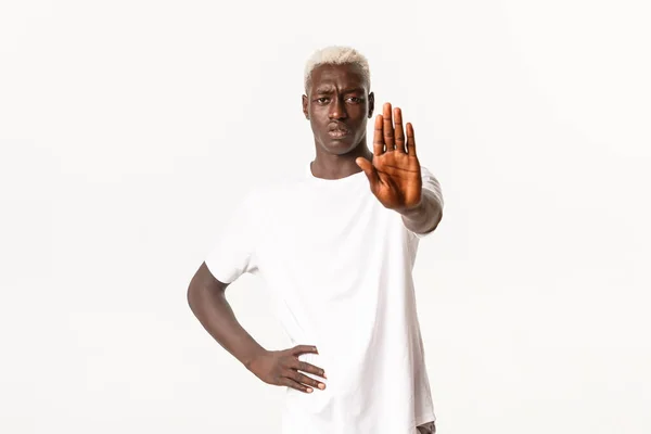 Retrato de hombre rubio afroamericano disgustado, extender la mano y mostrar gesto de stop, restringir algo, prohibir la acción, de pie fondo blanco — Foto de Stock