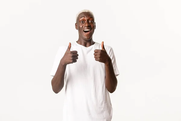 Portret van een blije en opgewonden knappe Afrikaans-Amerikaanse man, lachend verbaasd en met duimen omhoog in goedkeuring, als en beveel iets, witte achtergrond — Stockfoto