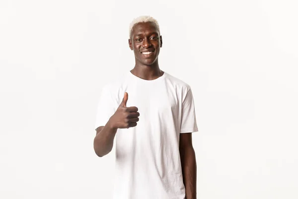 Retrato de un hombre afroamericano guapo sonriente mostrando el pulgar hacia arriba en aprobación, como algo bueno, de pie fondo blanco — Foto de Stock