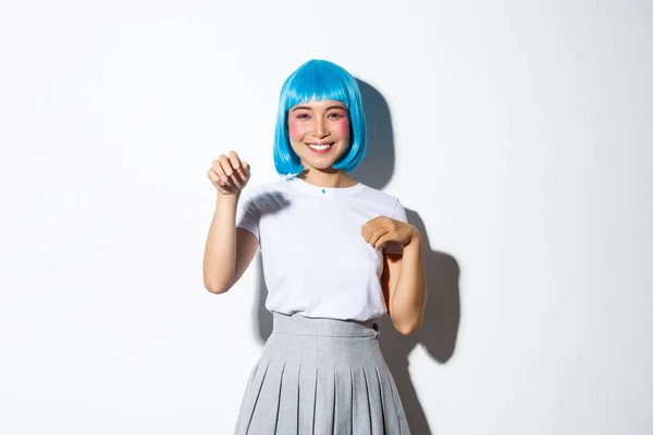 Portret zabawnej i uroczej koreańskiej dziewczyny w niebieskiej peruce świętującej halloween, machającej ręką jak łapa, stojącej nad białym tłem — Zdjęcie stockowe