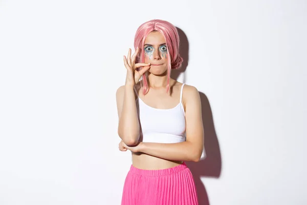 Imagem de menina festa engraçada em peruca rosa e maquiagem halloween, fazendo rosto sério ao fazer selo nos lábios, zíper boca como promessa de manter segredo, de pé sobre fundo branco — Fotografia de Stock
