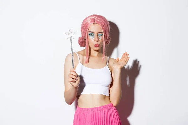Porträtt av attraktiv flicka cosplay älva för halloween, bär rosa peruk och hålla magiska trollspö, står över vit bakgrund — Stockfoto