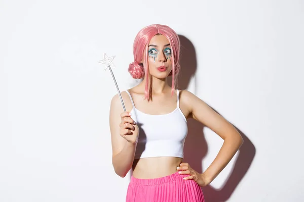 Εικόνα του όμορφη γυναίκα με ροζ περούκα και φωτεινό μακιγιάζ, κρατώντας μαγικό ραβδί, cosplay νεράιδα για αποκριές κόμμα, στέκεται πάνω από το λευκό φόντο — Φωτογραφία Αρχείου