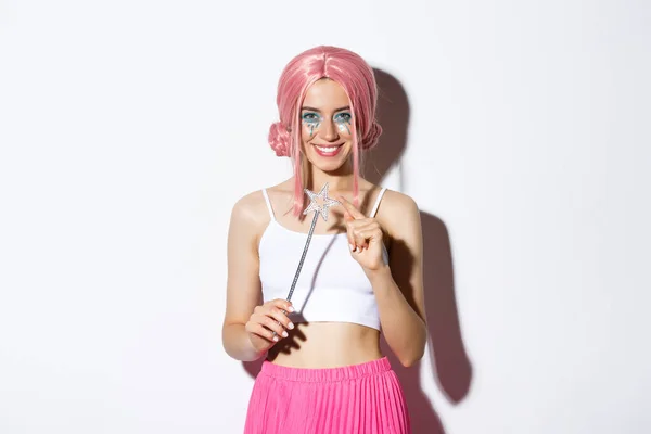 Porträtt av attraktiv flicka med rosa peruk och ljus makeup, utklädd till en älva för halloween fest, håller magiska trollspö och leende — Stockfoto