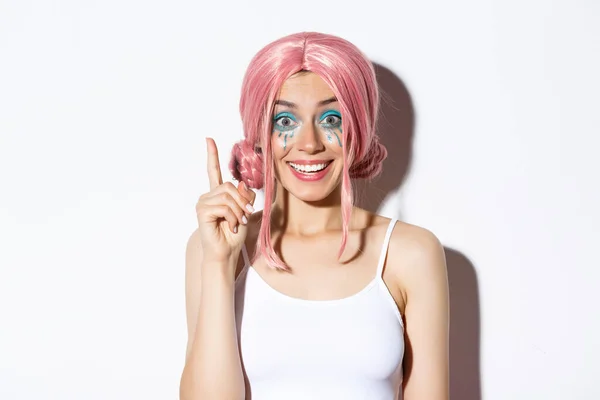 Zbliżenie kobiety w różowej peruce party i jasny makijaż, pomysł, podniesienie palca wskazującego w znak eureka, stojąc na białym tle — Zdjęcie stockowe