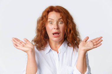 İnsanlar, duygular ve yaşam tarzı konsepti. Kafası karışmış ve şok olmuş, kafası karışmış, kafası karışmış, elleri yana açılmış ve ağzı açık bir şekilde endişeli bir kadın.
