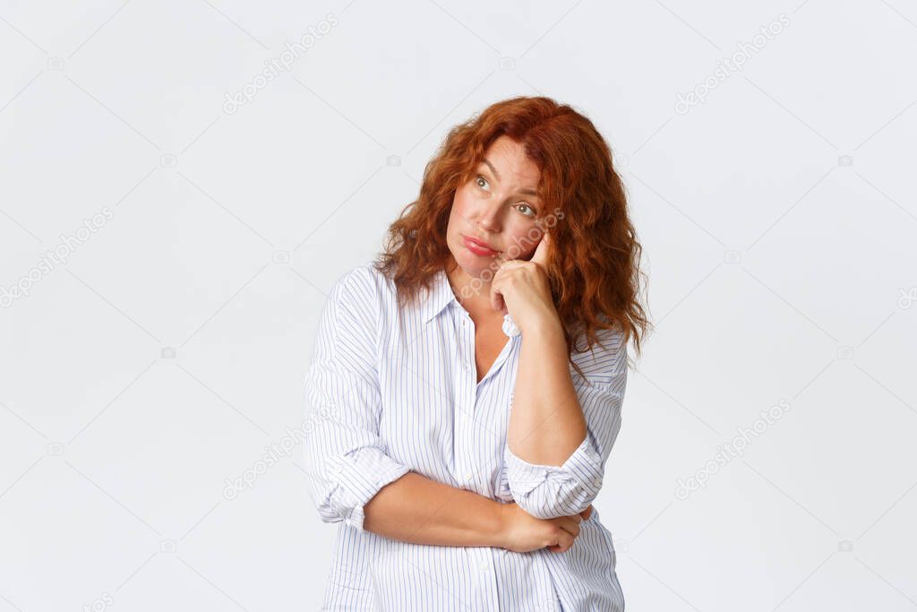 Annoyed and shocked middle-aged redhead woman rolling eyes and looking away bothered, tired of listening or having conversation, looking disappointed and distressed, white background