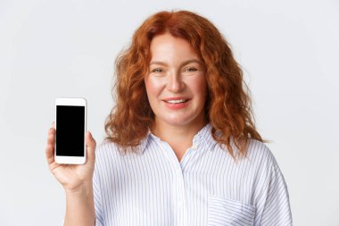 İnsanlar, duygular ve teknoloji kavramı. Akıllı telefon ekranı gösteren, gülümseyen, cep telefonu uygulaması ya da cep telefonu hizmeti öneren orta yaşlı güzel bir kadının yakın çekimi