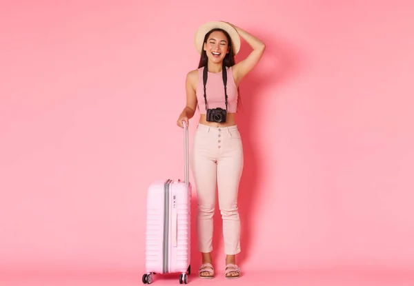 Turismo, férias de verão, férias no exterior conceito. Comprimento total de despreocupado menina bonita asiática em roupas de verão, chapéu de palha e câmera, fechar os olhos e sorrir em turnê, de pé com mala — Fotografia de Stock