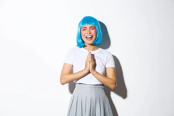 Retrato de chica asiática tonta en peluca azul pidiendo ayuda, suplicando mientras está de pie sobre fondo blanco — Foto de Stock