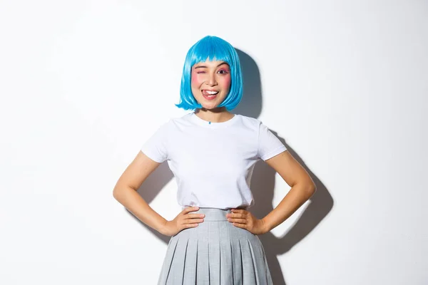 Portret pięknej azjatyckiej dziewczyny w niebieskiej peruce imprezowej pokazującej język i mrugające głupie, stojące na białym tle w stroju Kawaii halloween — Zdjęcie stockowe