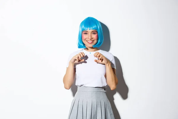 Portret pięknej azjatyckiej dziewczyny w niebieskiej peruce, cieszącej się halloween, uśmiechniętej i bawiącej się na imprezie, stojącej na białym tle — Zdjęcie stockowe