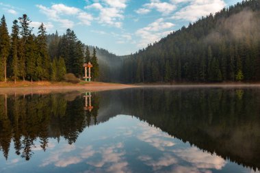 Sisli yüzey ve sabahın erken saatlerinde Synevyr Gölü 'nün orman yansıması. Güzel bir bahar sabahı Ukrayna 'nın en büyük dağ gölü..